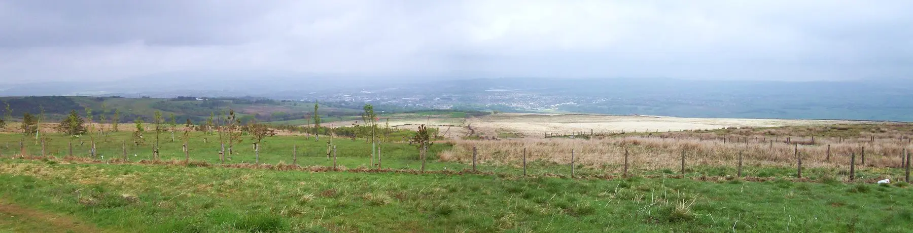 Rough grassland on the high ground at Crown Point, looking out across the valley towards Burnley under a grey sky.